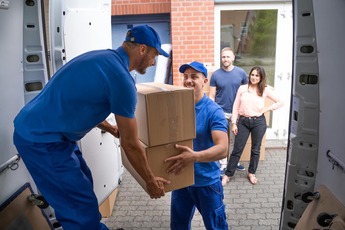 Movers carrying boxes into a residential home